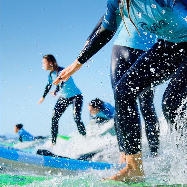 grupo de alumnos surfeando en clase de surf