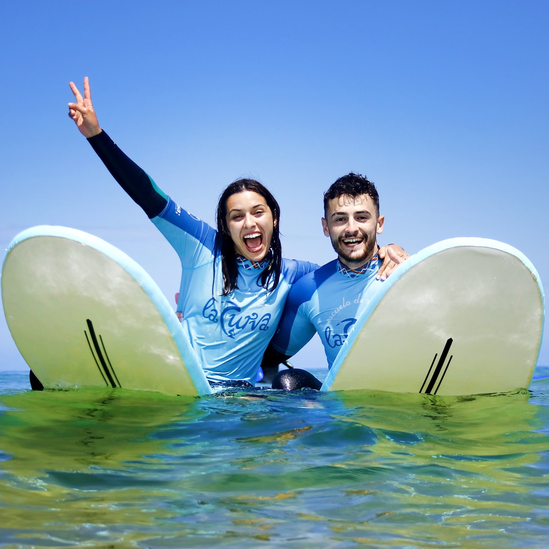 pareja posando en el agua con ñlas tablas de surf