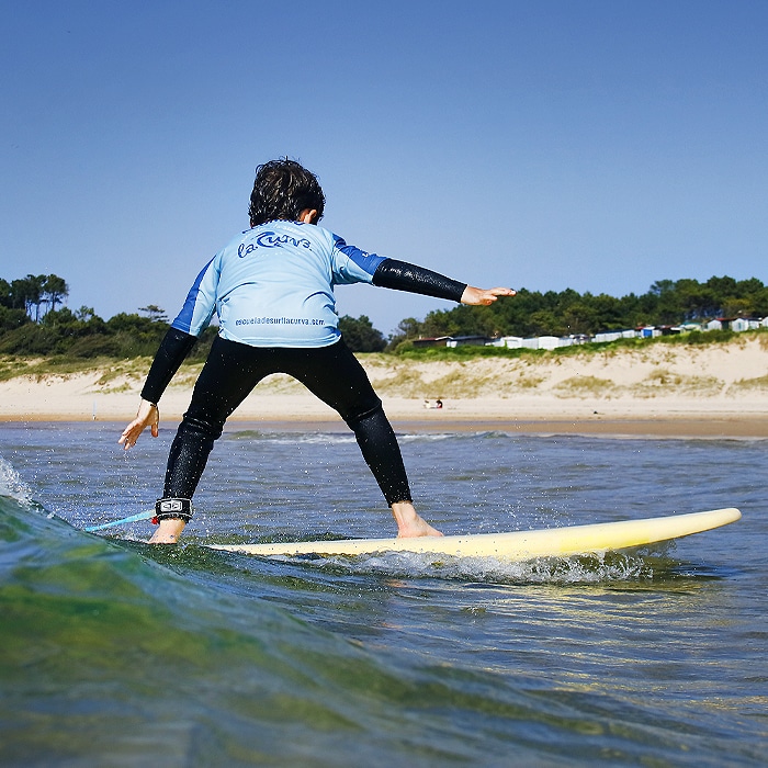 menor cogiendo una ola durante clase de surf