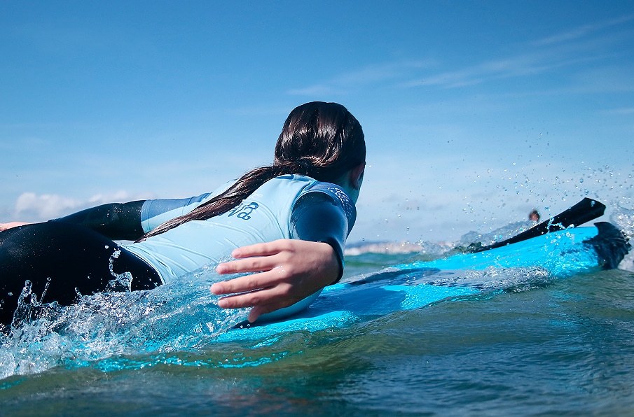 niña surfeando una ola en la Playa de Loredo Somo en el surf camp diurno
