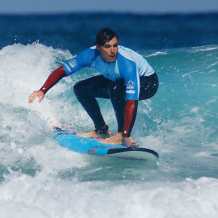 alumno surfeando durante clase de surf