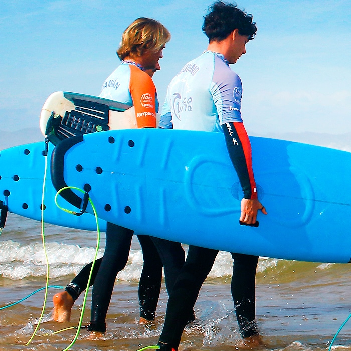 menores en la playa con el material de surf para clase